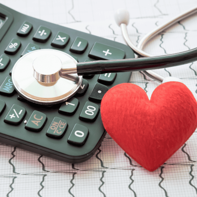 Items on a EKG printout: a calculator, stethoscope, and a red foam heart shape